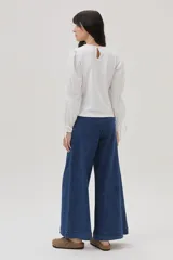 Blusa blanca de mangas largas abullonadas con puños elásticos y lazos.