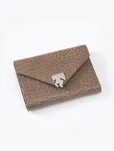 Billetera de cuero vacuno flor con textura graneada color marrón topo. Presenta un aplique metálico plateado con forma de llama en el frente y cierre magnético. El interior cuenta con múltiples ranuras para tarjetas y un bolsillo con cierre metálico.