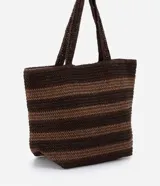 Bolso de playa tipo tote, confeccionado en paja color marrón con rayas horizontales negras.