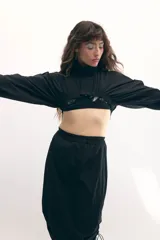 Campera cropped negra de tela técnica, con cuello alto, mangas murciélago y cierre frontal al tono.