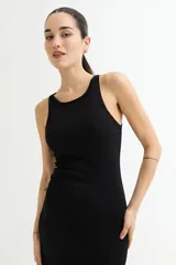 Vestido largo negro ajustado al cuerpo, sin mangas y con cuello redondo. Presenta una abertura lateral en el ruedo.