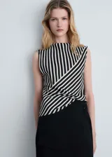 Blusa sin mangas de tejido fluido satinado con estampado de rayas verticales en blanco y negro, cuello Perkins y cierre de cremallera en la parte posterior.