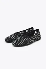 Zapato tipo bailarina color negro, con acabado en punta redonda y suela plana. Diseño de rejilla con tachas plateadas en todo el cuerpo.