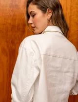Campera de denim blanca con cuello con solapa, abertura central con botones metálicos y bolsillos delanteros.
