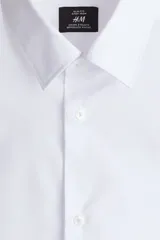Camisa blanca de corte slim fit, con cuello inglés, tapeta clásica, canesú en la espalda, mangas largas con puños abotonados y bajo levemente redondeado. Confeccionada en tela de fácil planchado.