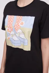 Remera negra con estampado de una mano sosteniendo una cartera rosa con flores.