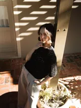 Suéter de punto de algodón negro con cuello redondo y mangas ¾.