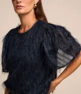 Blusa de chiffon color celeste, con cuello redondo, mangas cortas con fruncidos en los hombros y textura con felpas.