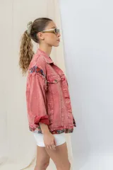 Campera de jean oversize, color rojo desgastado, con aplicaciones de tapicería multicolor de estilo étnico en hombros y ruedo, y terminaciones desflecadas.