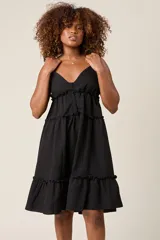 Vestido corto lila con breteles finos, escote en V con botones y falda escalonada con volados.