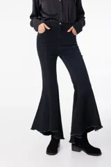 Pantalón de jean elastizado negro con corte acampanado y volados en el ruedo.