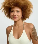 Blusa cropped de frente única color crema, confeccionada en algodón con elastano, con escote en V y lazo en el cuello.