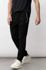 Pantalón de jogging negro con cintura elástica ajustable con cordón, bolsillos laterales con cierre y logo pequeño en la pierna izquierda.