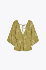 Top color verde oliva con estampado floral en jacquard, escote en pico pronunciado, mangas cortas abullonadas con elástico, cintura elástica y espalda descubierta ajustable con lazos.