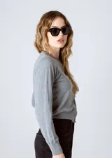 Cardigan gris de tejido de punto con cuello redondo y cierre frontal con botones.