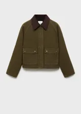 Chaqueta corta color verde militar, con cuello camisero de pana marrón, cierre frontal con cremallera oculta, dos bolsillos con solapa en el pecho y forro interior.