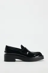 Mocasín negro de charol con detalle de antifaz en el empeine y punta redonda.