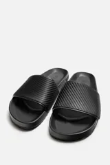 Sandalias tipo pala color beige con tira ancha en el empeine con relieve y suela de goma con volumen.