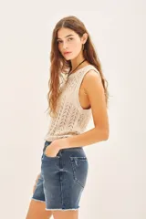 Musculosa sin mangas de tejido punto desagujado en color beige claro, con patrón de rombos calados y brillo sutil por el hilado de lurex y lentejuelas.