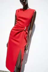Vestido midi rojo de cuello redondo y sin mangas, con detalle de pliegues y fornitura en la cintura, y abertura frontal en el bajo.