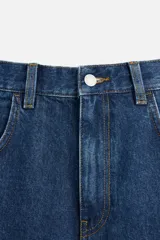 Bermuda de jean color negro, corte amplio, con cinco bolsillos, efecto lavado y cierre frontal con cremallera y botón.
