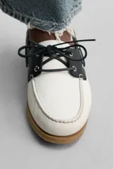 Zapato náutico de cuero blanco con detalles en negro y suela marrón. Edición limitada con horma redonda y plantilla de cuero.