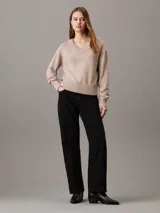 Sweater de punto color rosa pálido con cuello en V y logo bordado en el pecho.