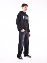 Buzo hoodie negro con cordones ajustables y bolsillo tipo canguro. Estampado frontal con diseño de montañas y texto 'Restless. Explore More'.