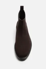 Bota Chelsea de cuero marrón oscuro con elásticos laterales negros, tirador trasero y suela plana.