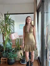Vestido corto negro con escote en V, tiras finas que se atan al cuello y falda con volados.