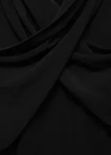 Camiseta negra de cuello alto con diseño cruzado y mangas largas.