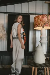 Pantalón de vestir color beige, de corte palazzo, con bordado de flores negras en el ruedo.