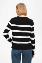 Sweater de punto negro con rayas horizontales blancas, cuello redondo y mangas largas.
