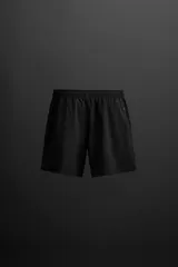 Shorts de entrenamiento negros confeccionados en tejido técnico ligero y elástico, con cintura elástica ajustable con cordón interior, bolsillos frontales y bolsillo trasero con cierre de cremallera. Bajo con acabado termofijado y aberturas laterales.