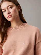 Sweater de punto color salmón, de corte relaxed, con cuello redondo y monograma bordado de Calvin Klein en el pecho.