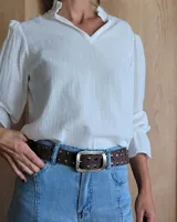 Cinto marrón de cuero con tachas plateadas y doradas, y hebilla metálica rectangular color bronce.