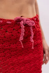 Minifalda tejida a crochet color rojo con cordón de ajuste rosa en la cintura.