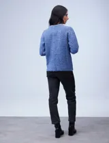 Buzo de tejido melange color beige con puntos oscuros, cuello redondo y manga larga.