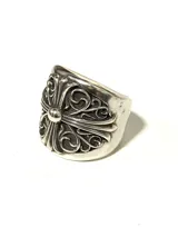 Anillo plateado con diseño de cruz gótica ornamentada con volutas. Fabricado en aleación con baño plateado, acabado envejecido y textura marcada.
