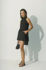 Top sin mangas blanco con cuello alto y bajo asimétrico, de textura arrugada.