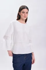 Blusa de muselina color crudo, de corte recto, con cuello redondo y mangas largas acampanadas con detalle de vainillas.