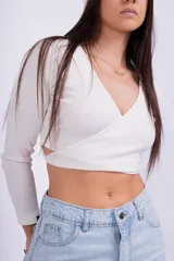 Remera corta gris de punto con escote cruzado y mangas largas.