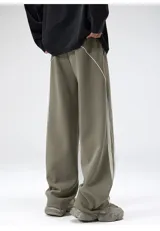 Pantalón deportivo estilo jogging, color verde oliva, con cintura ajustable con cordón y bolsillos laterales. Presenta una franja lateral doble en color blanco.