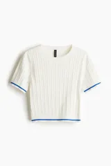Top corto blanco de punto trenzado con cuello redondo y mangas cortas con ribete azul.