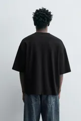 Camiseta negra de corte cuadrado (boxy fit), cuello redondo y mangas cortas. Detalle de costuras en delantero y espalda.