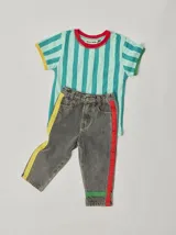 Pantalón de jean celeste con efecto lavado, corte recto y largo a la rodilla. Presenta una cinta vertical color violeta en la pierna izquierda, una cinta vertical color verde en la pierna derecha y una cinta horizontal color rosa en la parte inferior de ambas piernas.