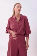 Camisa de manga larga color rosado oscuro/terracota, con cuello camisero y botones frontales. Presenta un calce holgado y tejido con caída.
