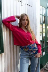 Camisa roja simil lino, de corte recto, con cuello camisero y cierre frontal con botones.