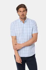 Camisa de manga corta con botones, color celeste con estampado a cuadros blancos. Hecha en Uruguay.