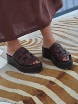 Sandalias negras de cuero con plataforma pareja y tiras de cuero tejidas en la parte superior.